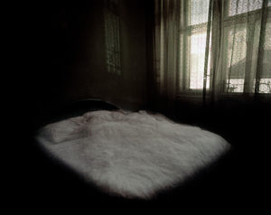 Tirage photo pigmentaire, lit dans une chambre sombre, rideaux dentelle